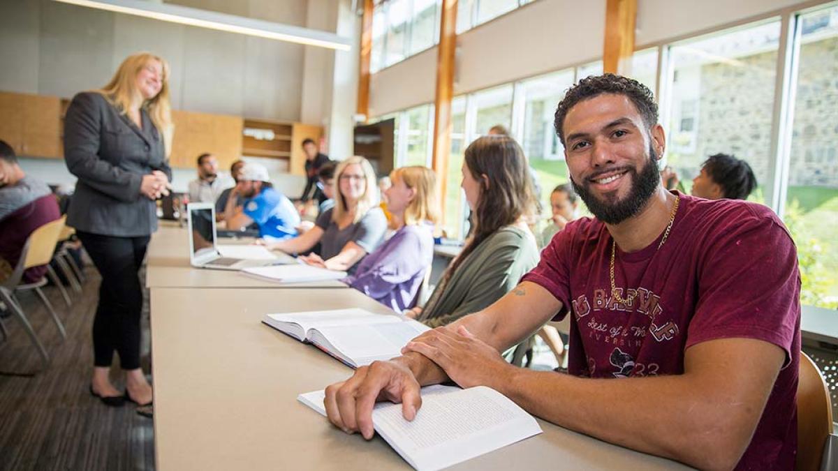 Pace University student sitting in a classroom, smiling at the camera.
