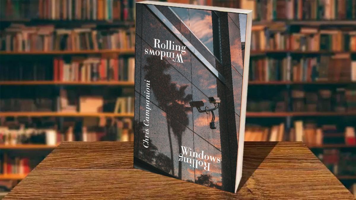 Cover of Chris Campanioni's latest publication, Rolling Windows, in front of a bookshelf. The title and author's name are printed in white text over a reflective side of an wall of windows with a security camera. 