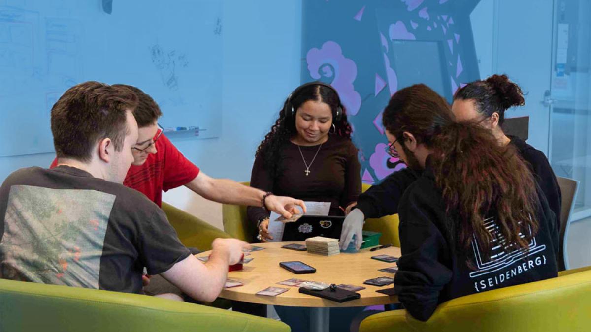 Seidenberg students sitting at a table and playing a card game.
