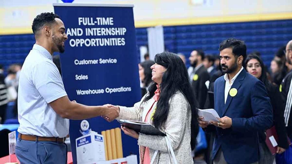 A Pace University student shakes hands with an employer at the job and internship fair