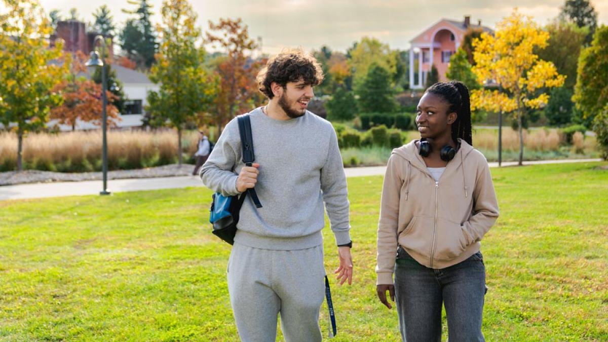 Students walking on the quad with Choate House in the distance behind them.
