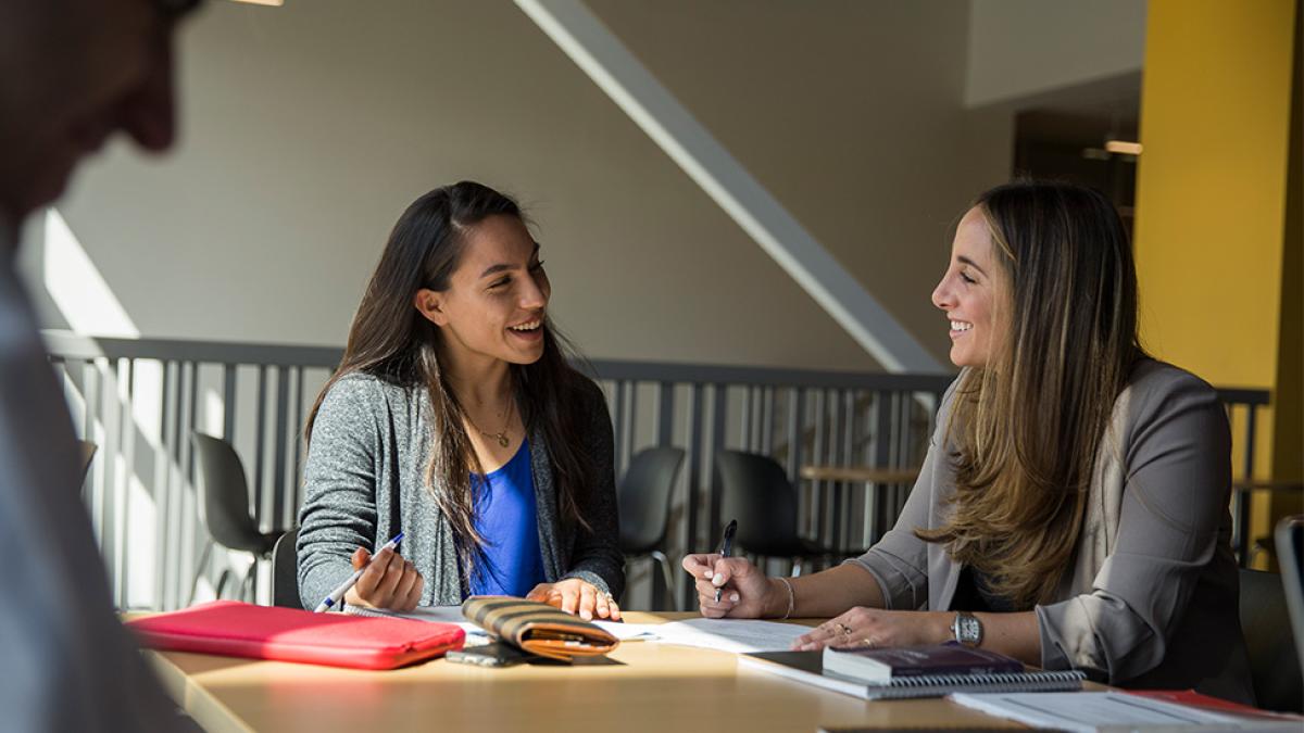 Two women sit at a table, studying