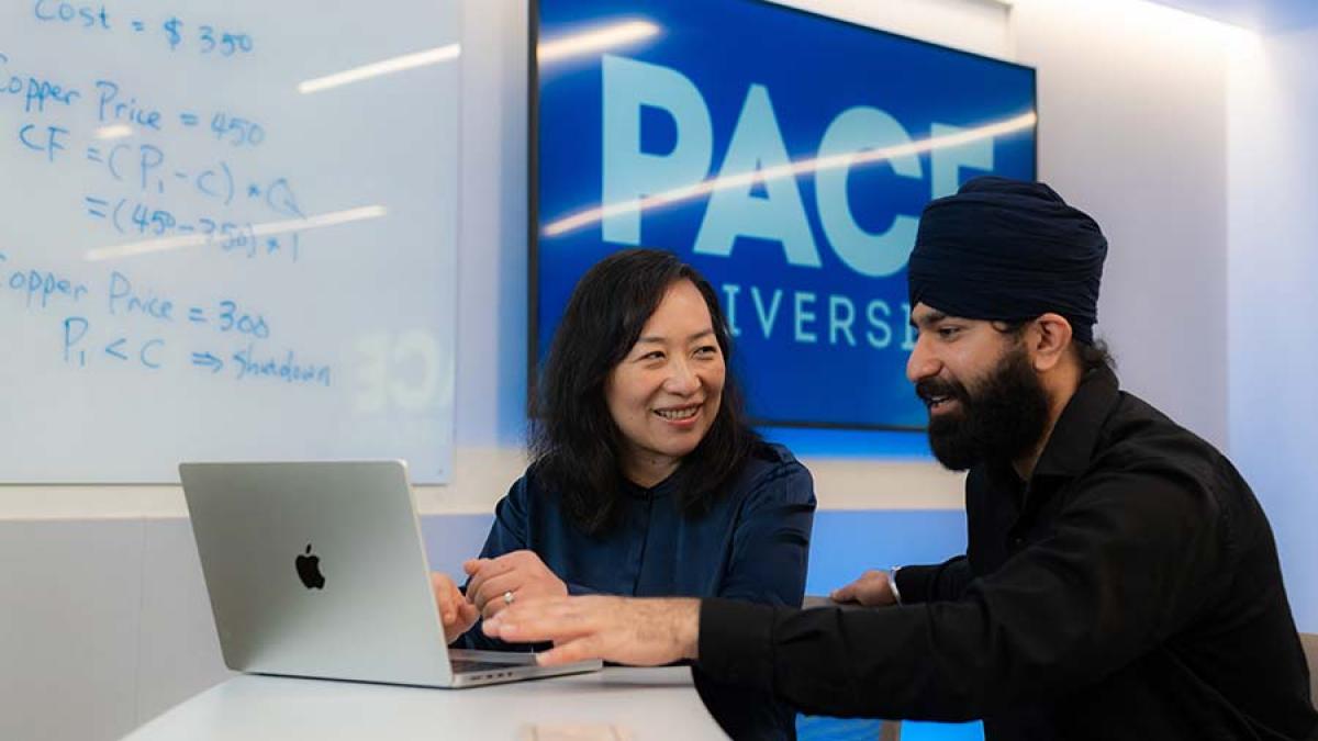 Three Pace University Lubin School of Business students and faculty speaking together at a laptop