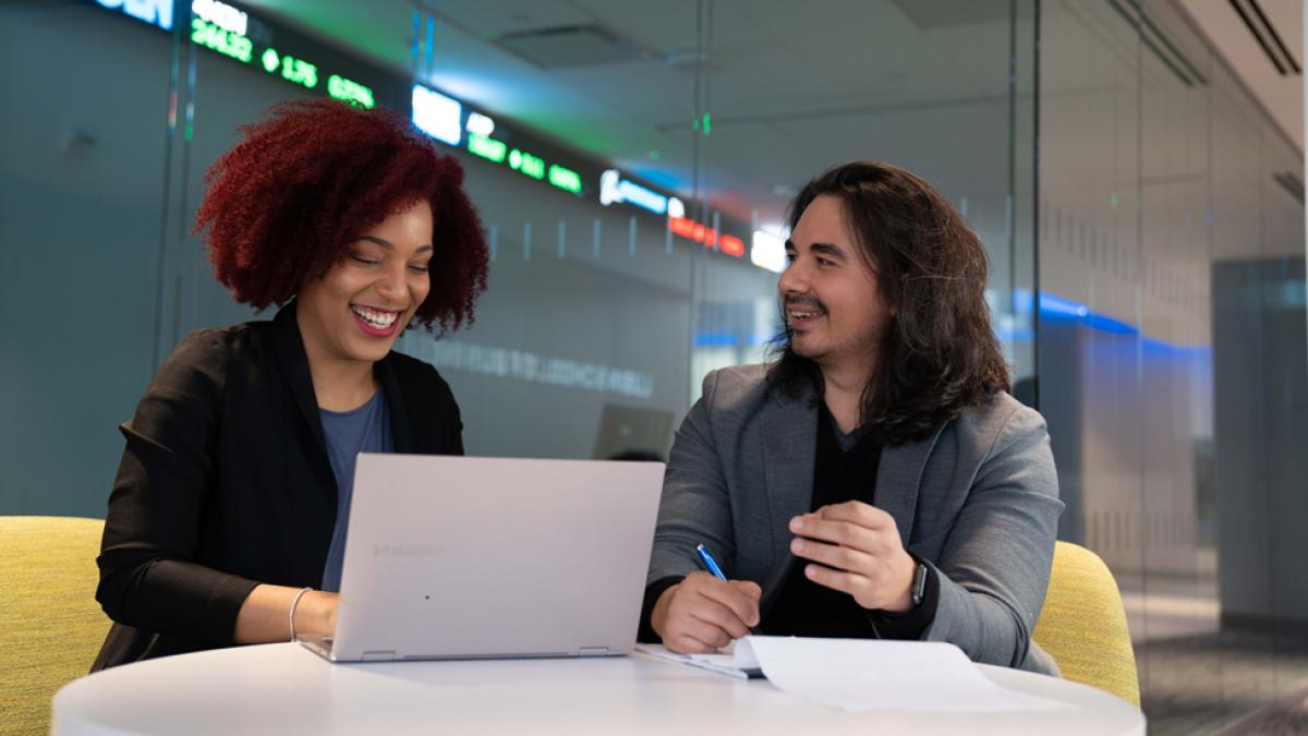 Two Pace University graduate students sitting at a table working on a laptop.
