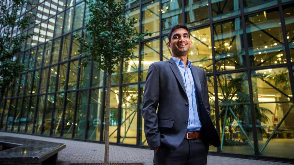 Pace University graduate student dressed in business attire, standing in front of a building in NYC.