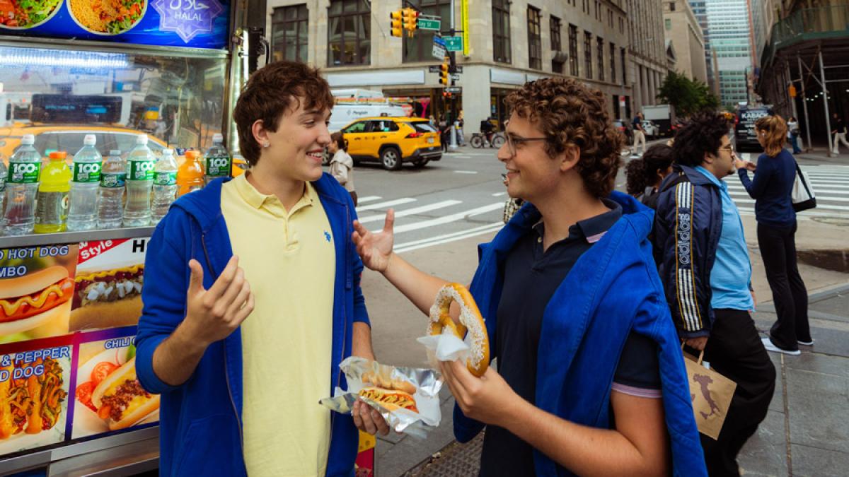 Two Pace University students eating pretzels in front of a food truck in NYC.