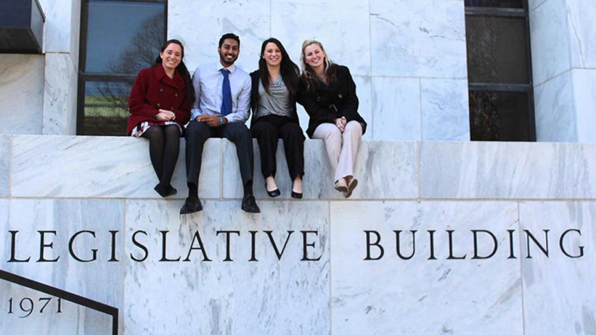 Four Pace students sitting atop the balcony of the NYS Legislative Building