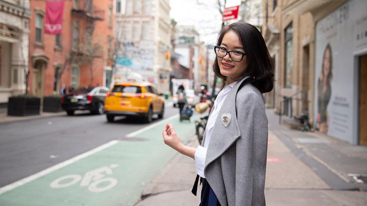 Pace University student wearing a jacket with New York City street in the background