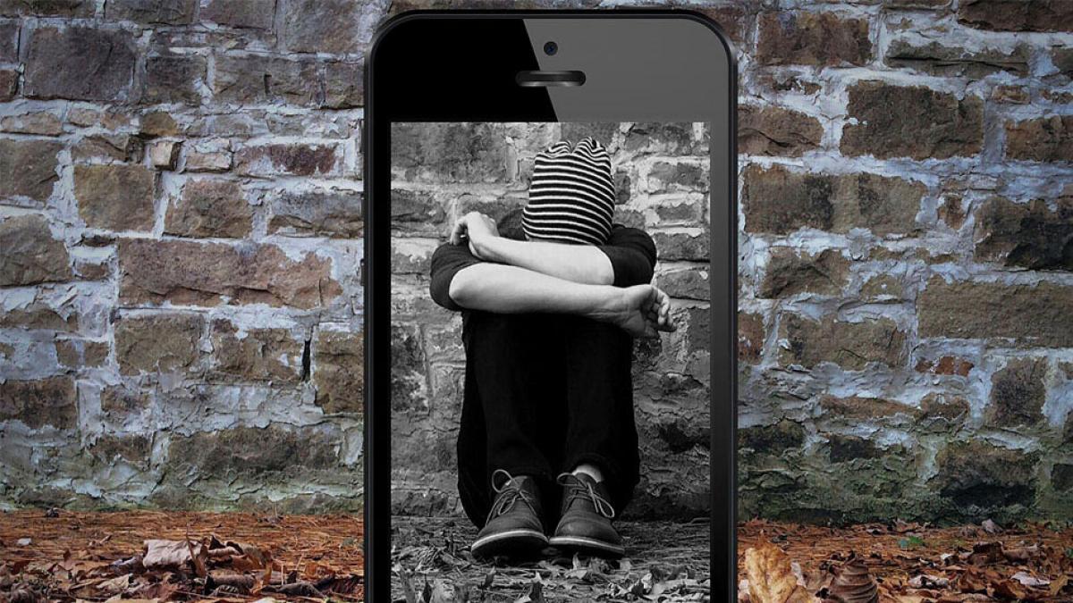 mobile phone with image of hooded person representing victim of revenge porn cybercrime