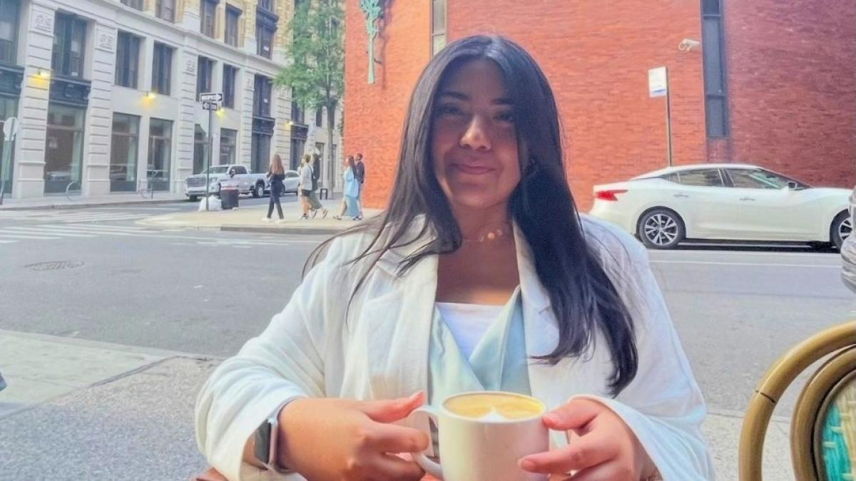 Seidenberg alum Laraib Sarmad sitting with a cup of coffee at a cafe in NYC