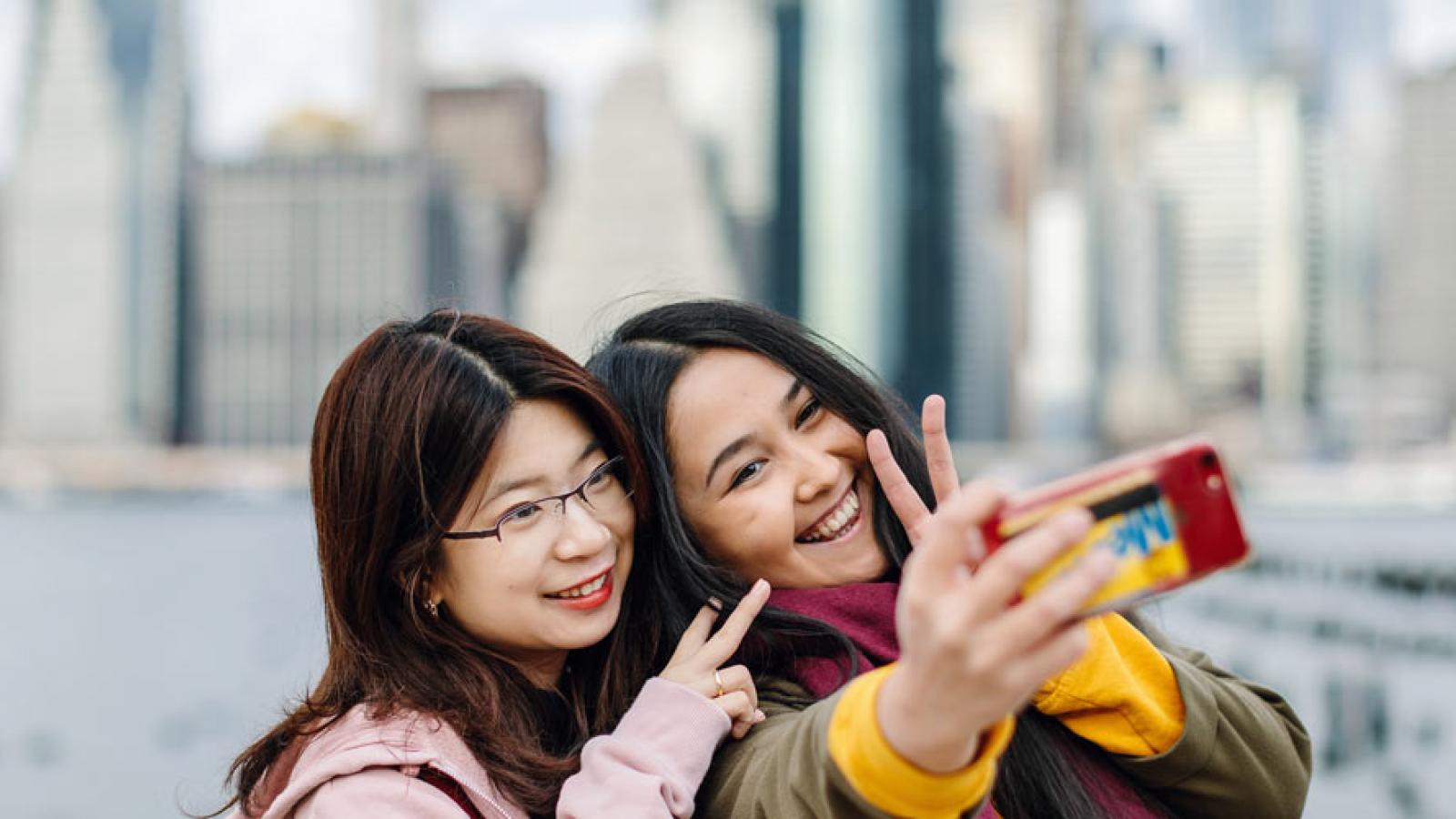 Students take a selfie in front of NYC skyline.