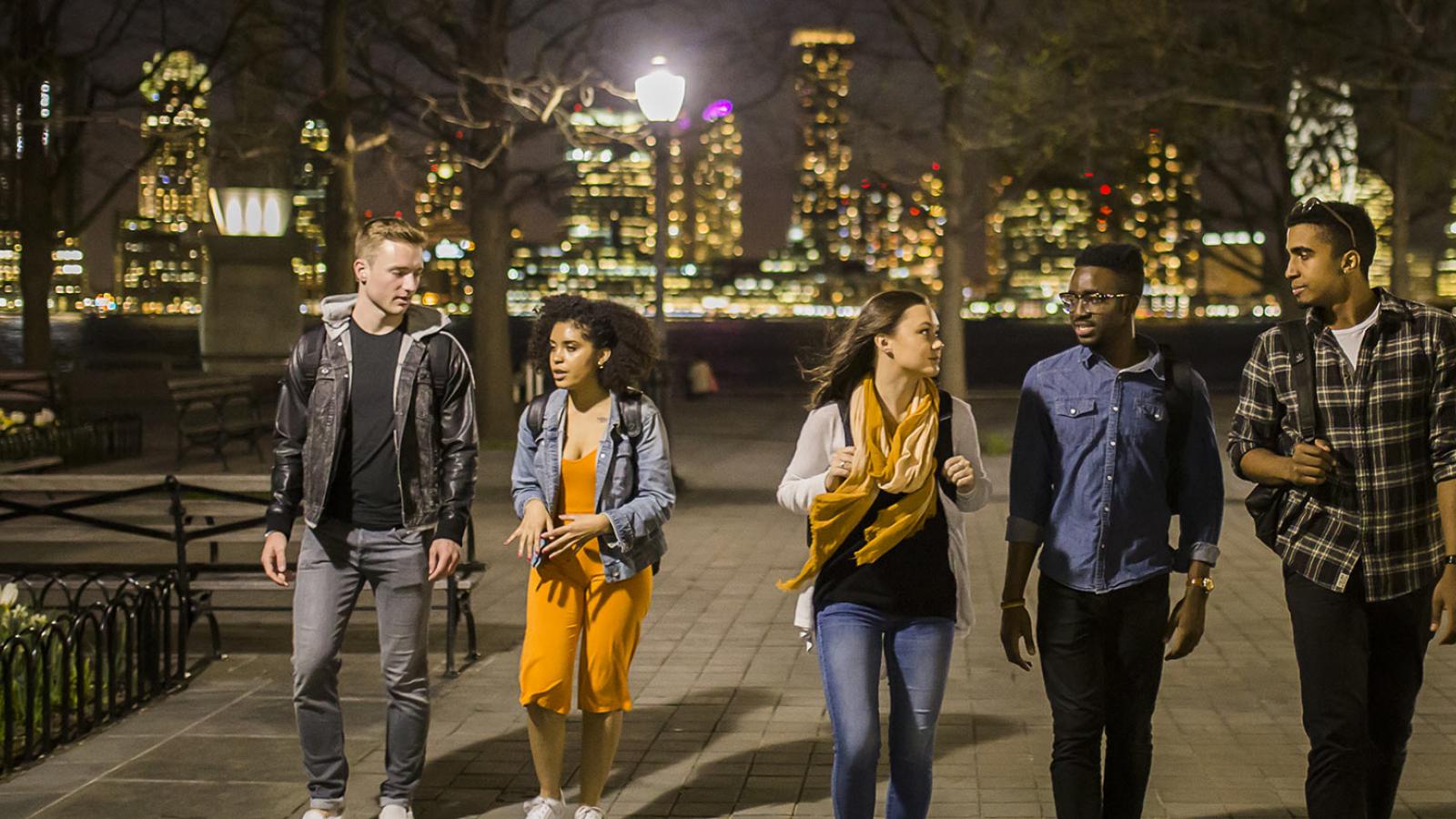 Five Pace students walking through a park at night.