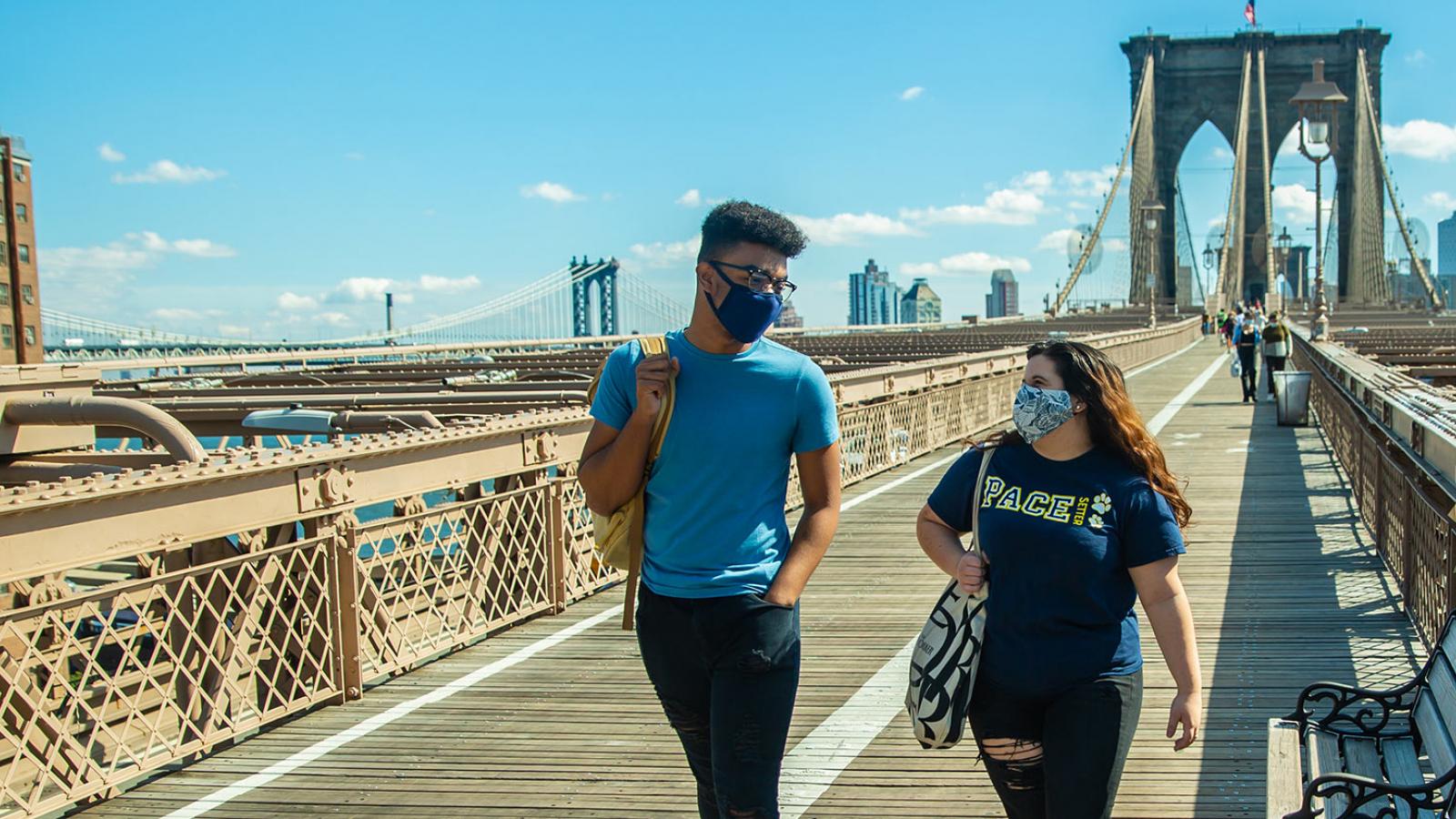 Two Pace University students walking across the Brooklyn Bridge