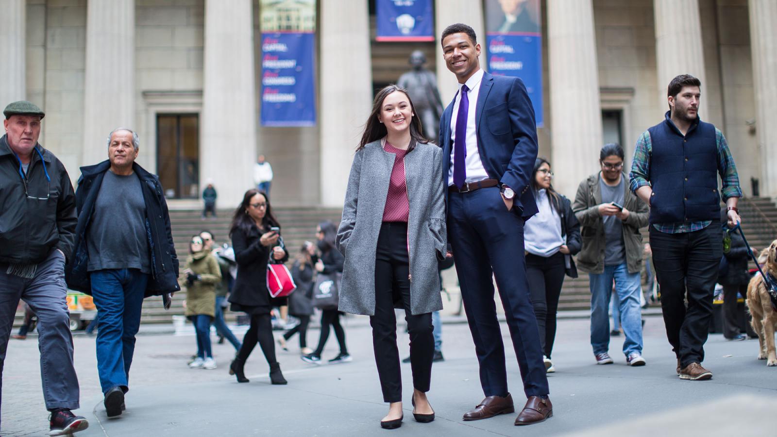 Two people dressed in business attire walking in NYC