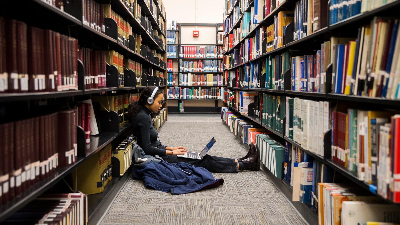 Student sitting on the floor studying at the library.