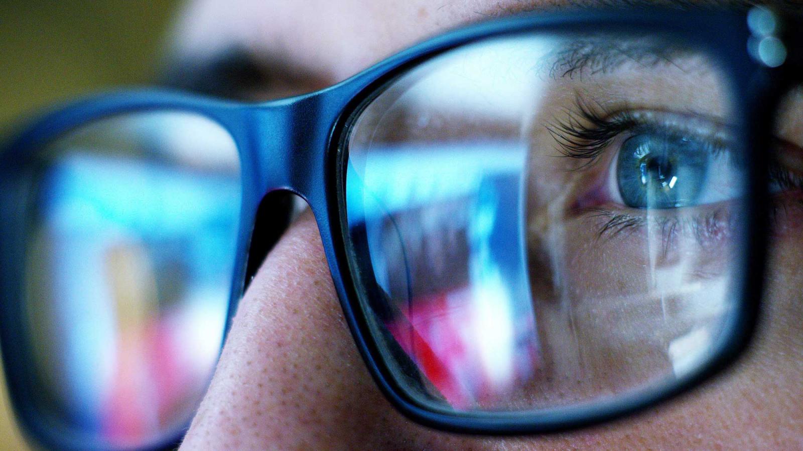 close up of eyeglasses and eye reflecting a computer screen
