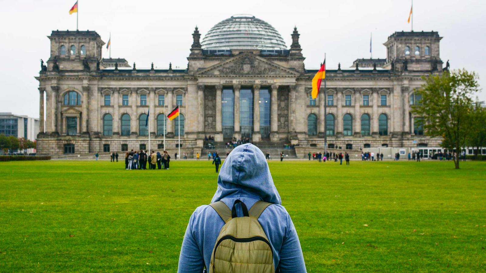 person in backpack and hoodie looking at a german building