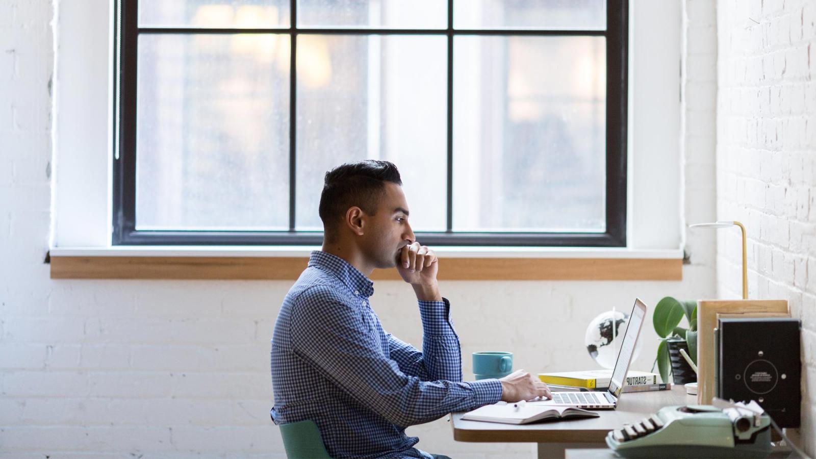 young man at a desk looking at a laptop