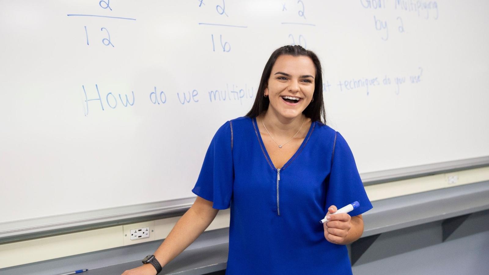 Female teacher laughing by whiteboard