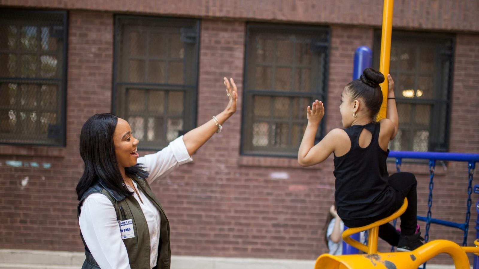 Teacher and Student High-Fiving on Playground