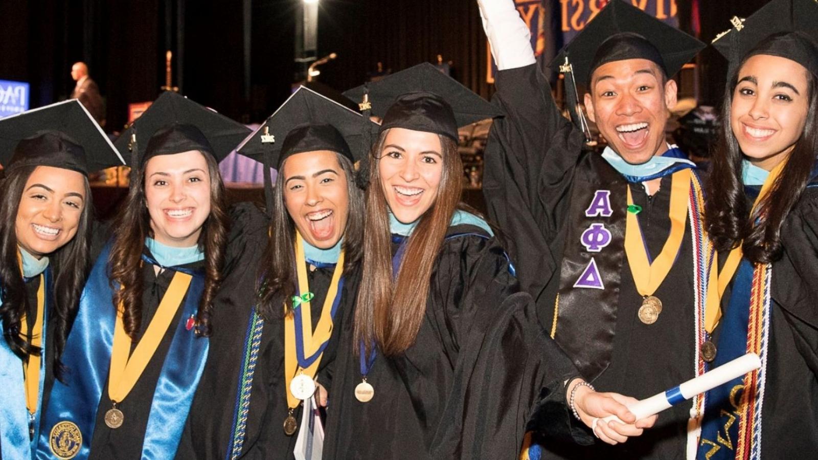 graduates in cap and gown smiling wearing medallions