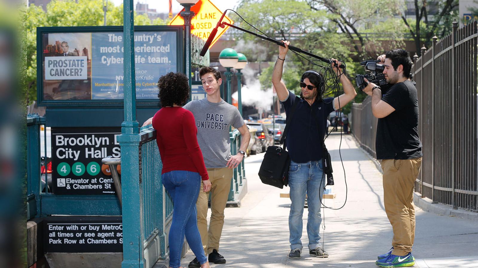Students outside of One Pace Plaza at Brooklyn Bridge 4,5,6 station sidewalk entrance with camera equipment