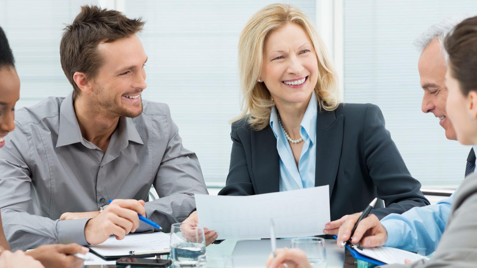 Workers in business attire sitting around a conference table representing the Center for Global Governance, Reporting, and Regulation