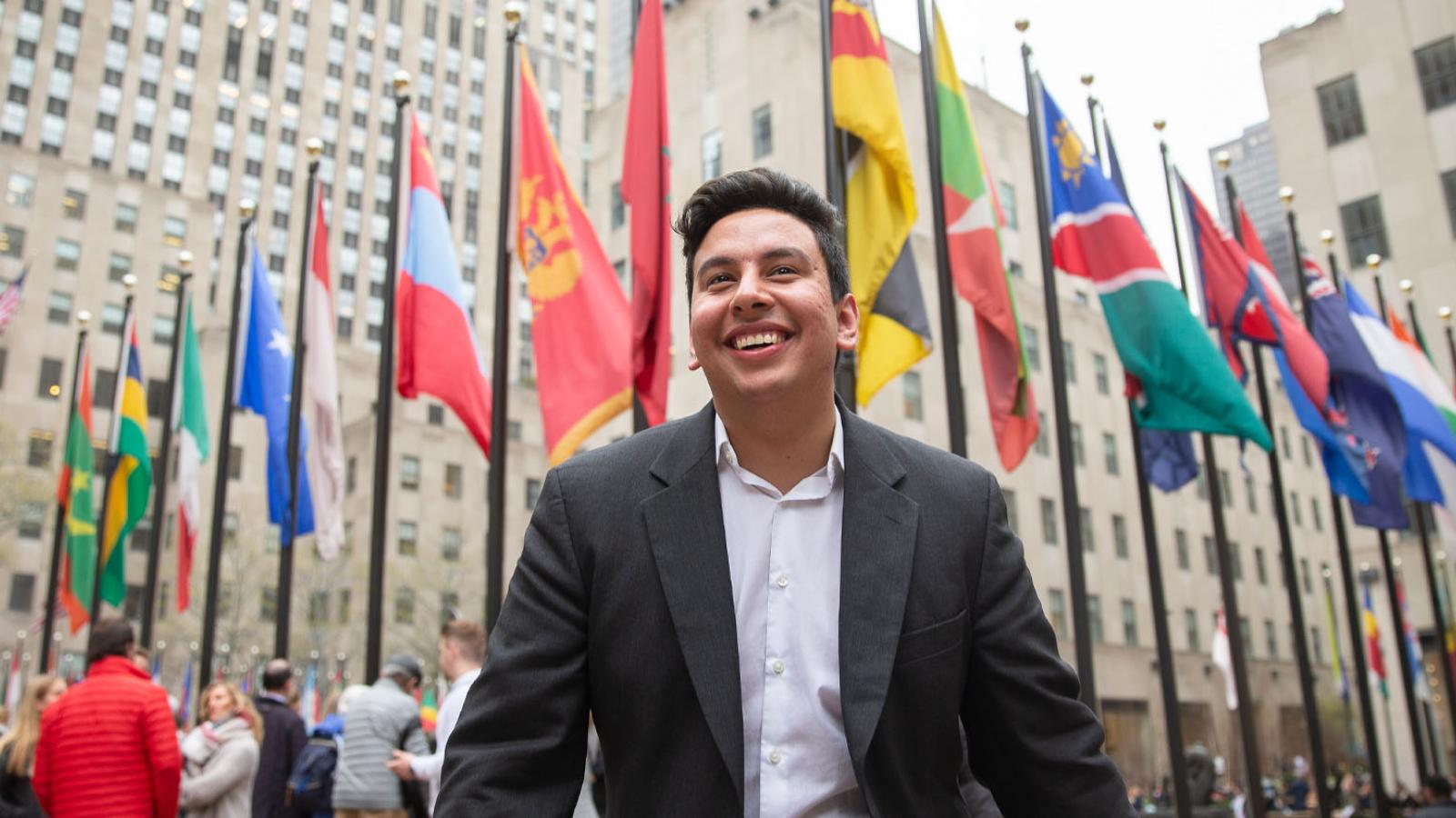 Young man standing in front of a row of world flags in New York City