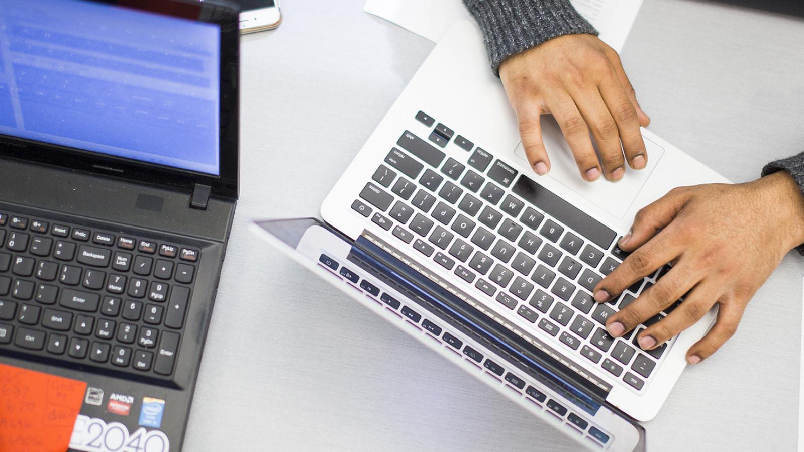 Hands typing on a laptop