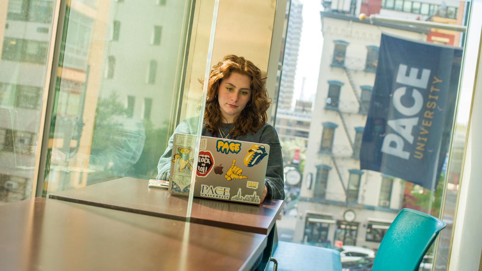 Student working on her laptop, sitting at a desk.