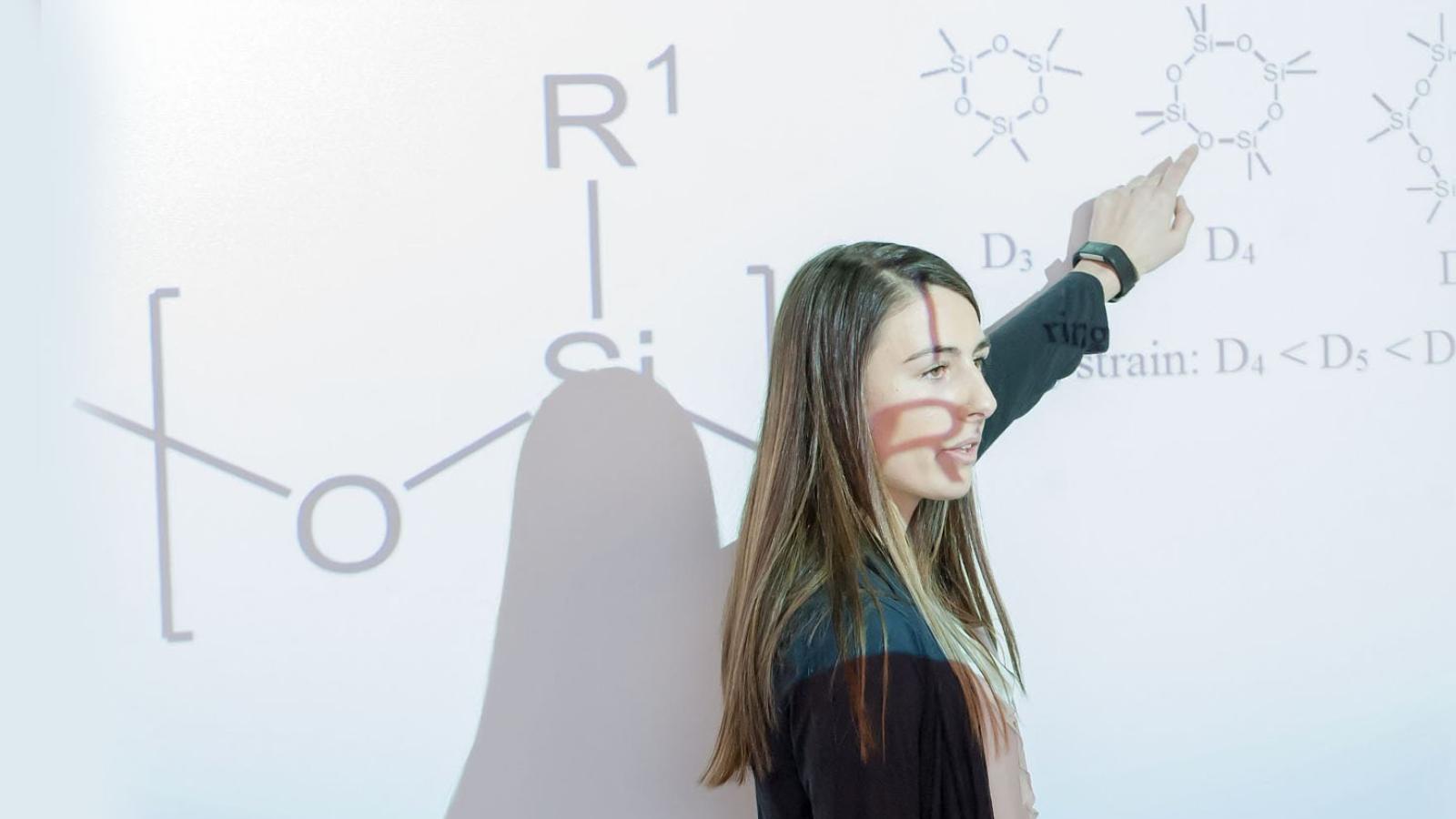 Kayleigh Ryan pointing at research through a projection