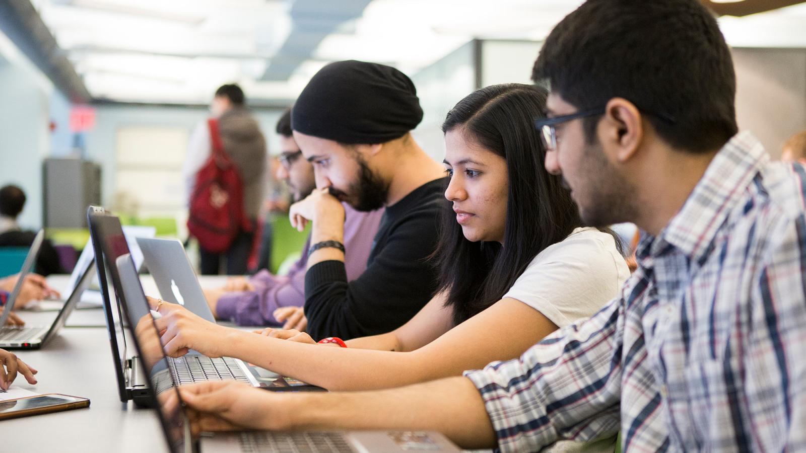 Group of students from the Seidenberg School of Computer Science and Information Systems working on their computers.