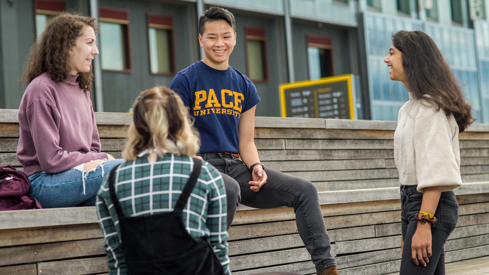 four students sitting and chatting outside