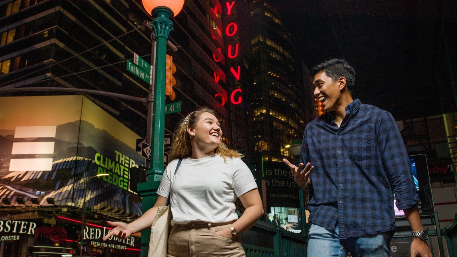 man and woman walking and laughing in times square new york city