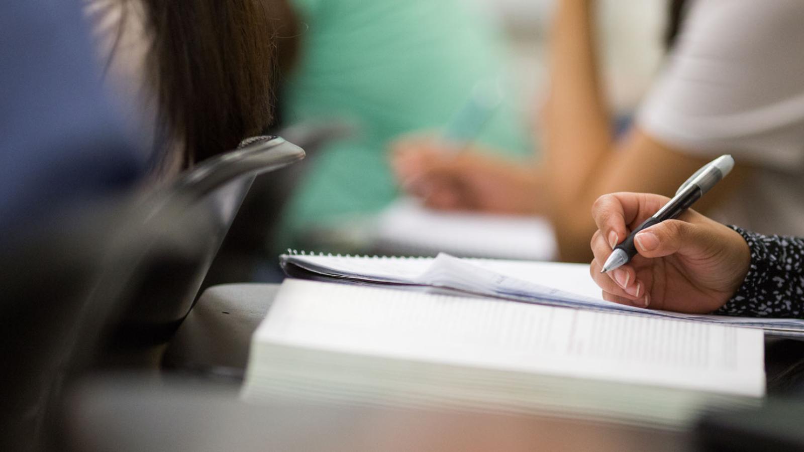close-up of Lubin student writing at a desk in a classroom on the New York City Campus