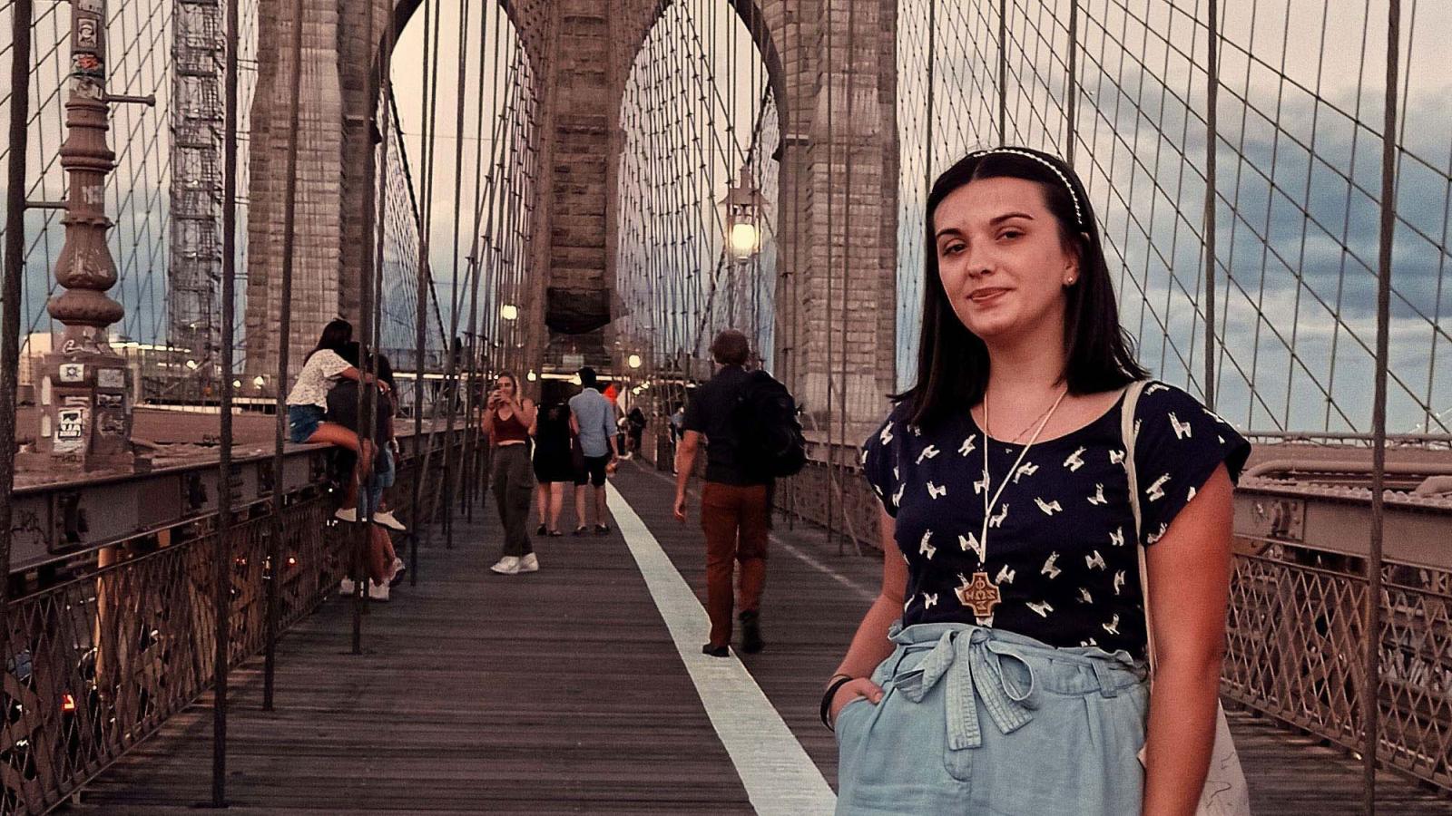 Julia Sroczy stands and smiles on a bridge in New York City