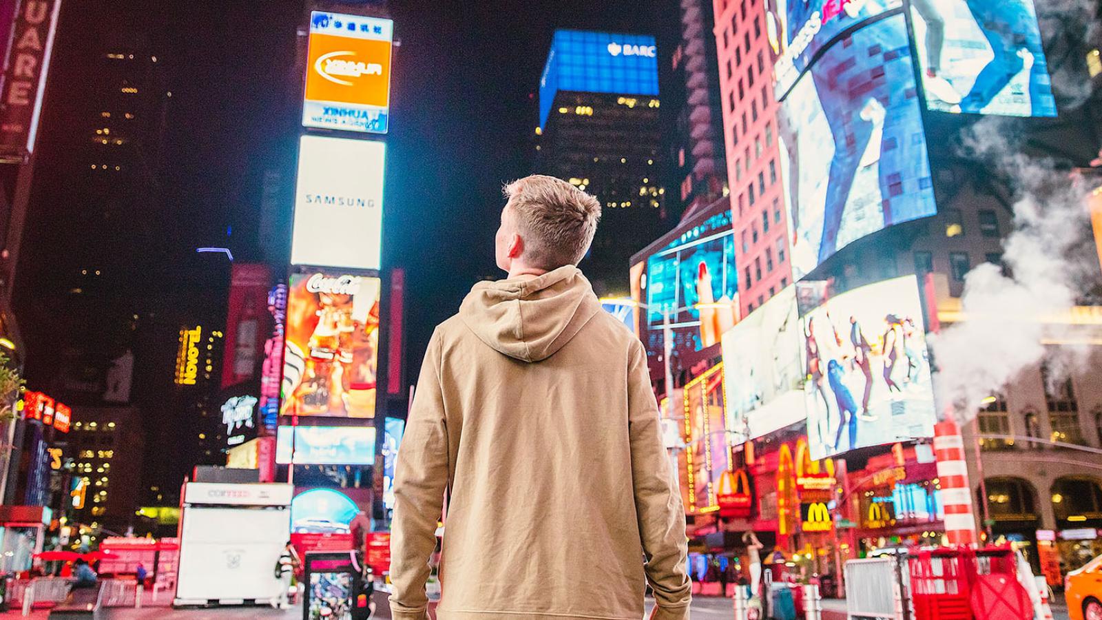 Individual standing in Times Square looking at the advertising and billboards 