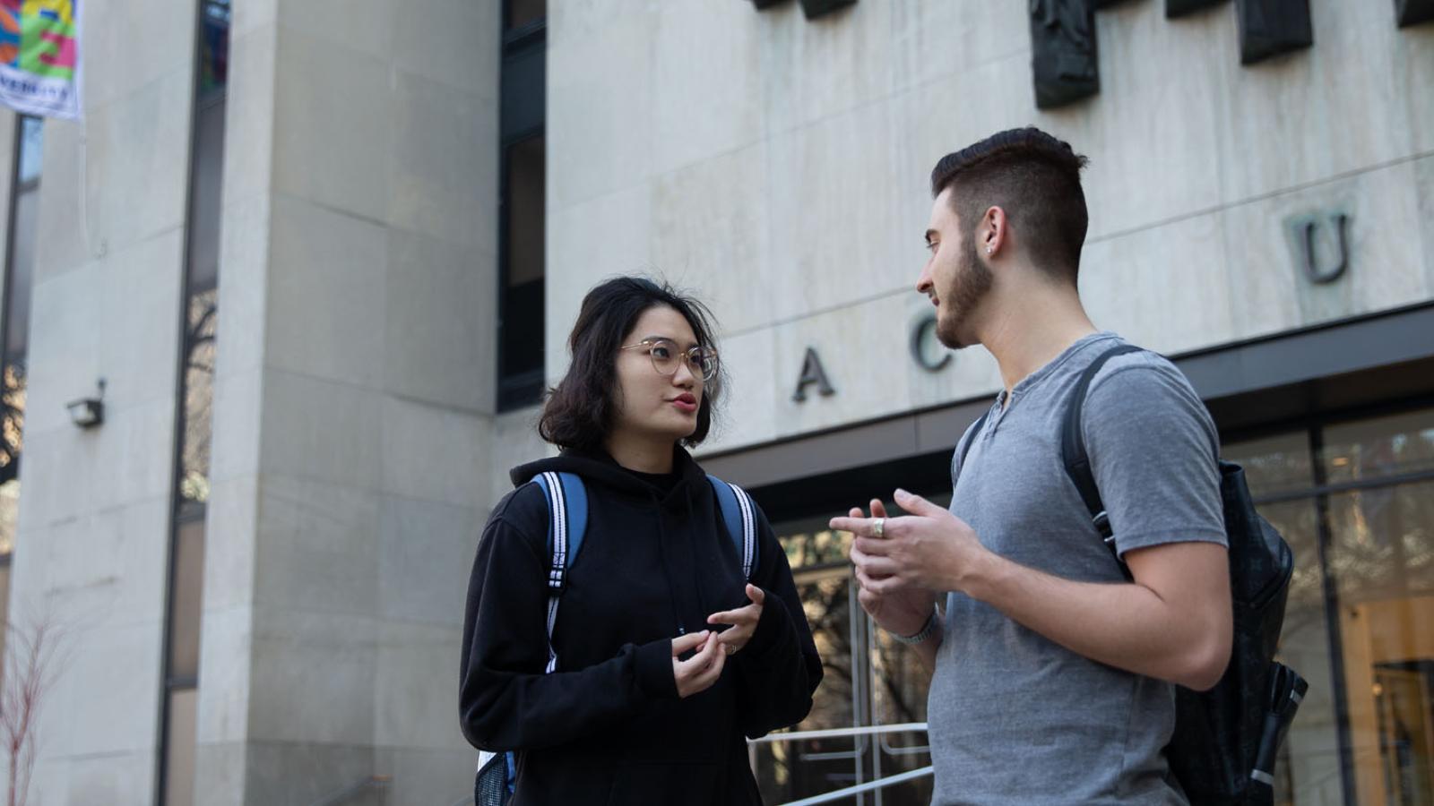 two Lubin students standing in front of One Pace Plaza on the New York City Campus in Lower Manhattan