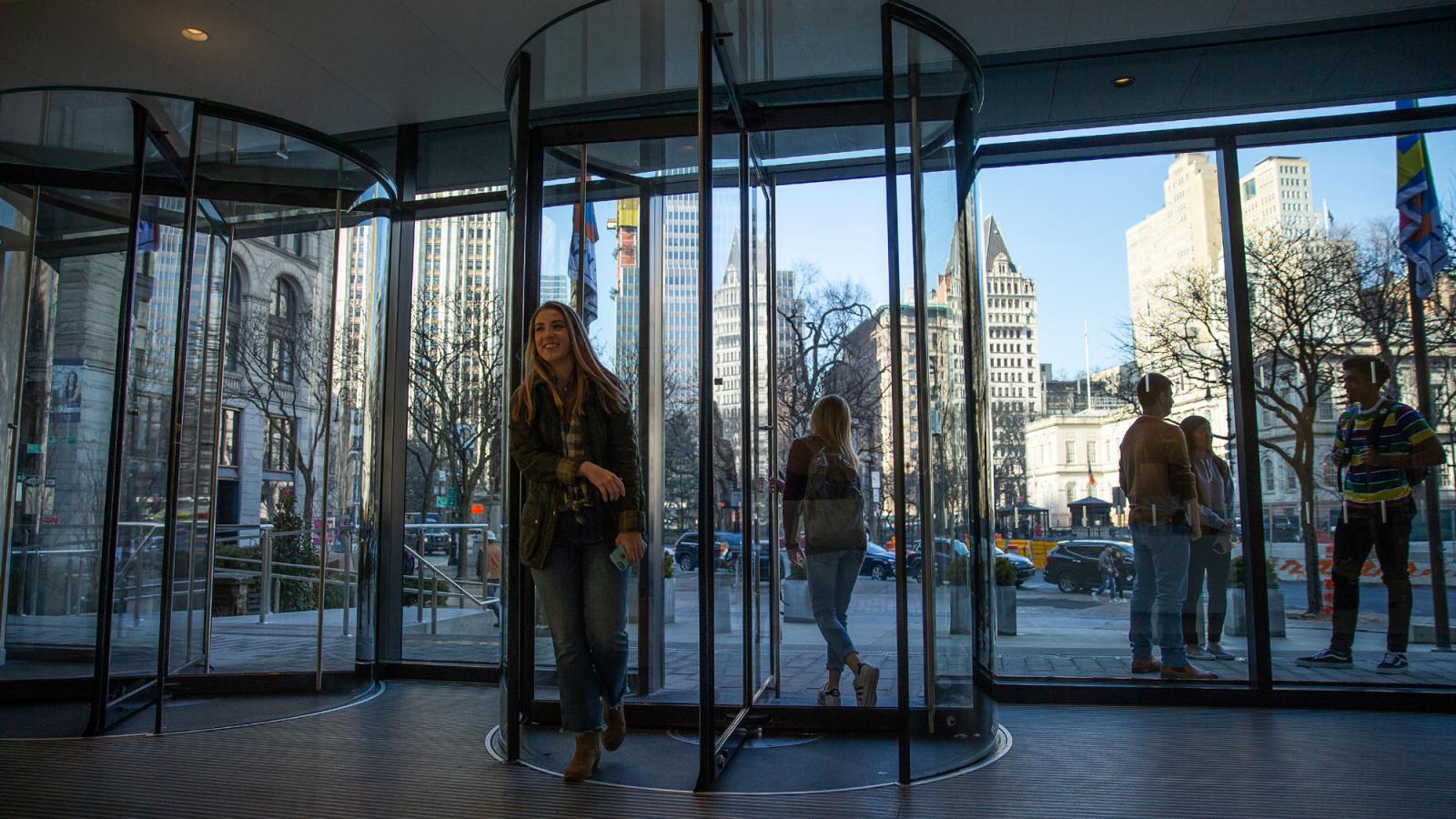 Pace students walking through revolving doors of One Pace Plaza at the New York City Campus