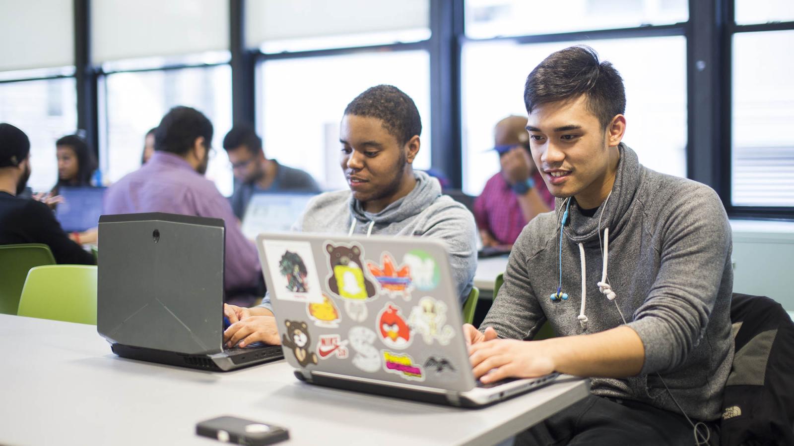 Two students working on their laptops.