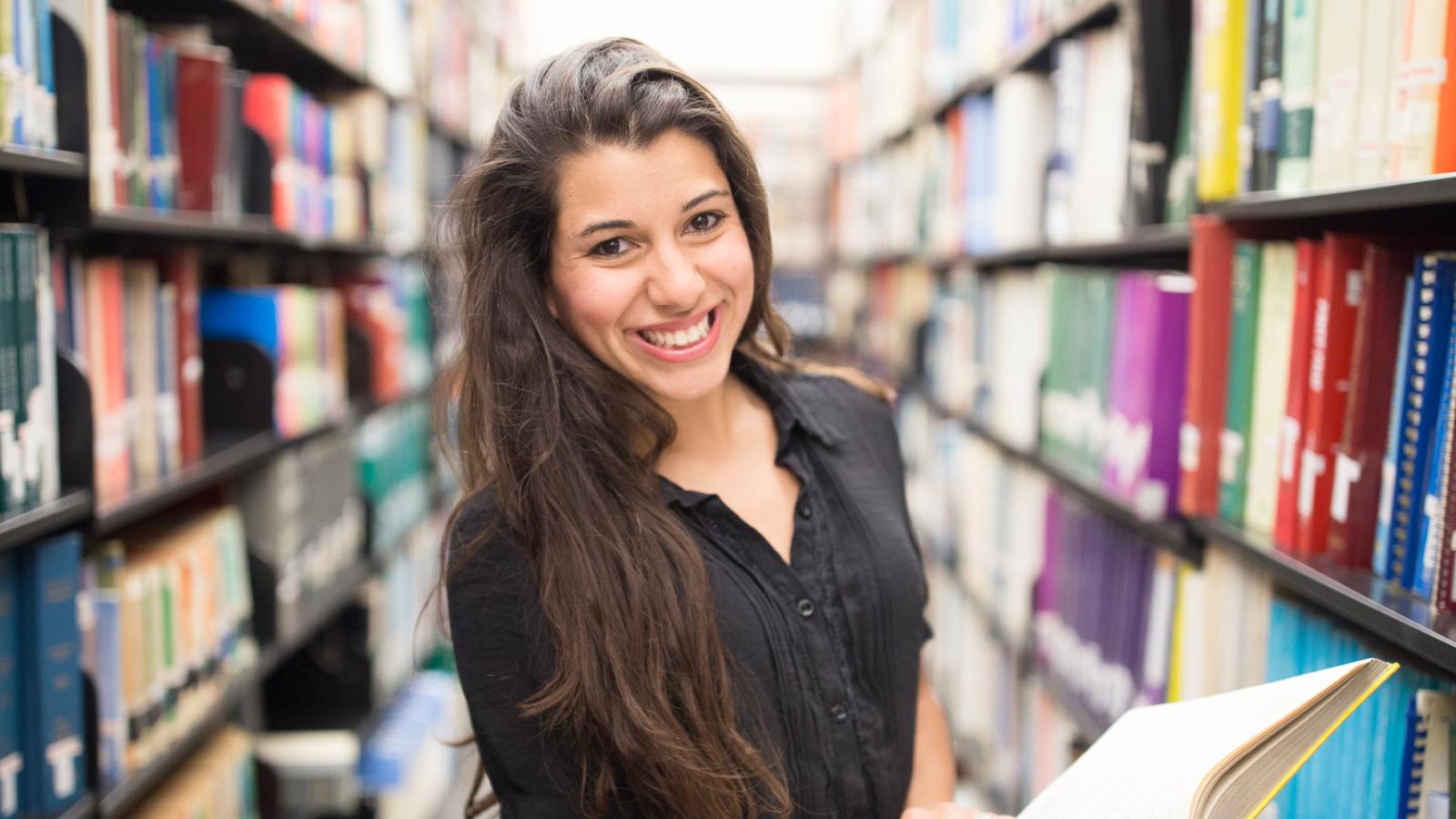 Female student holding book in library