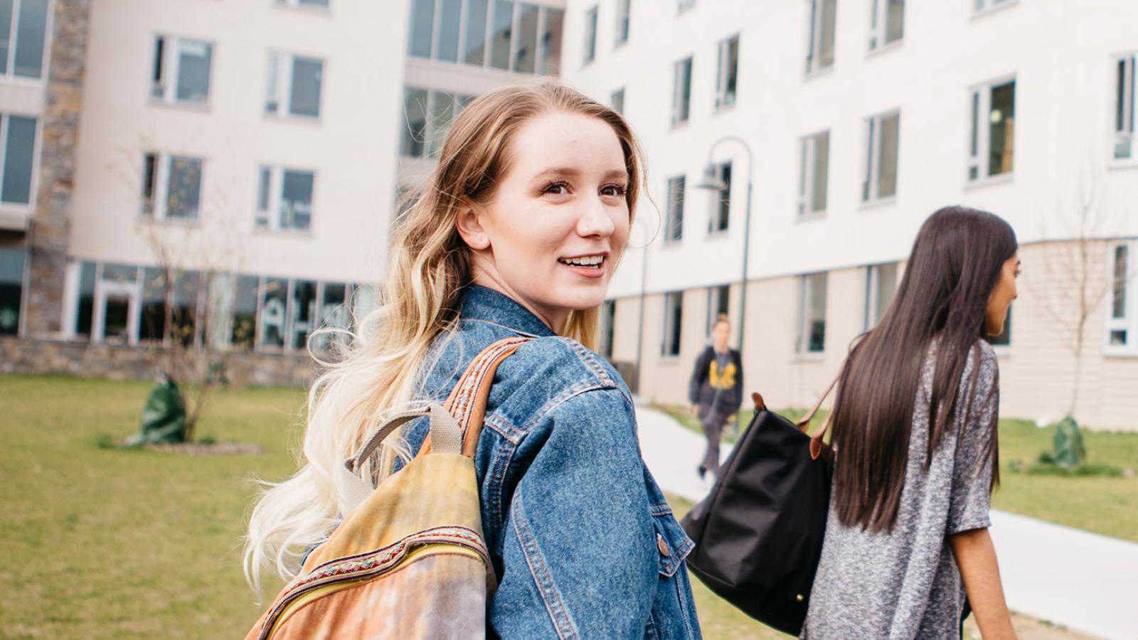 Student walking on the Westchester campus smiling at the camera.