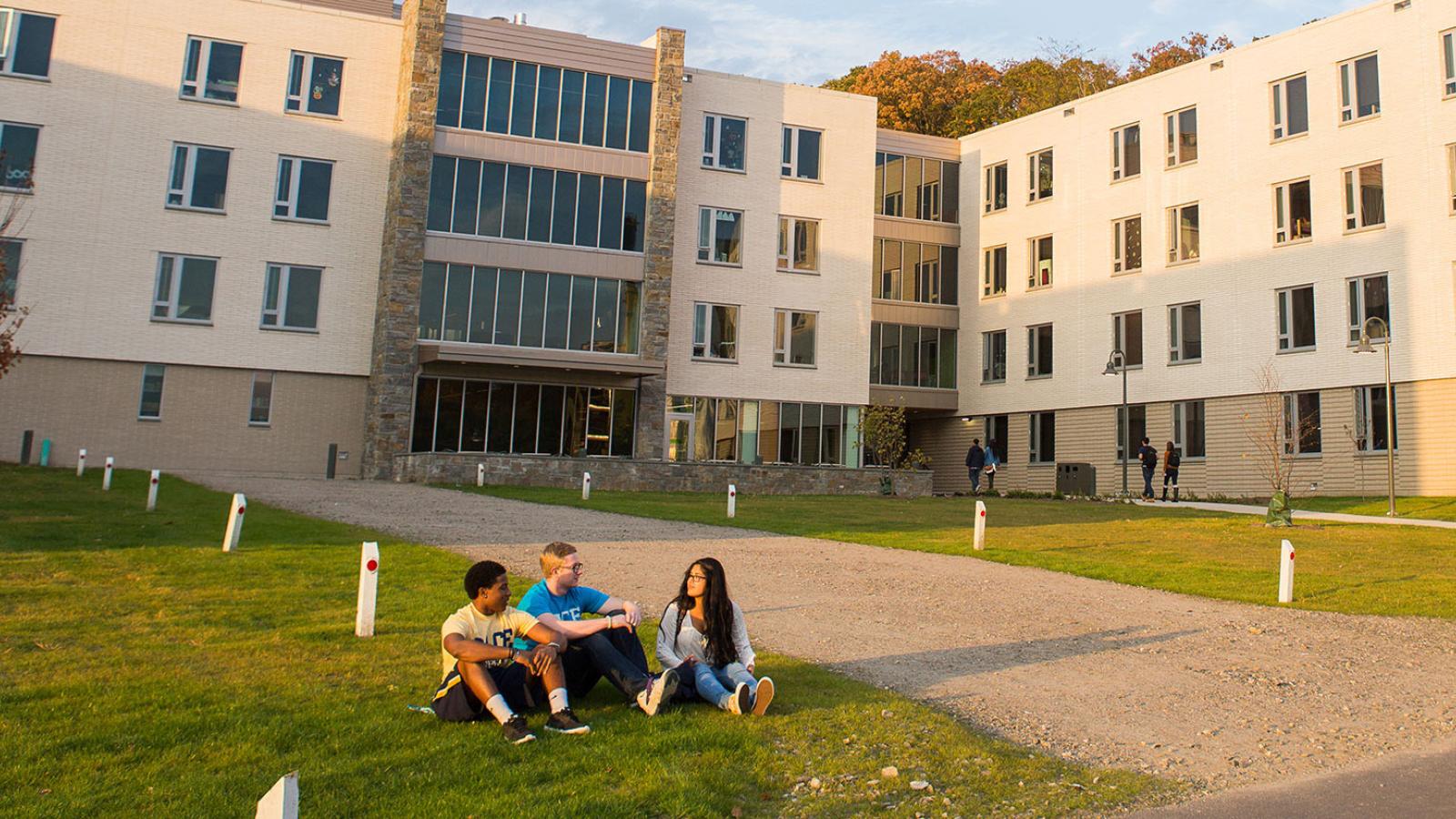 Students sitting on the lawn in front of a residential hall.