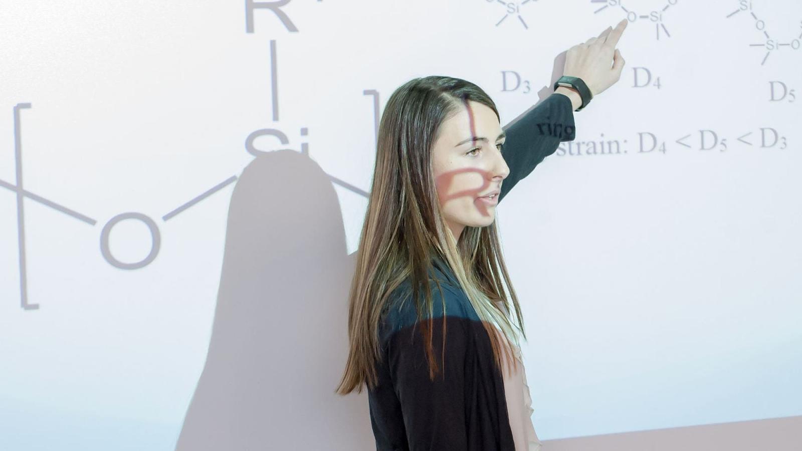 Student pointing at formulas through a projection