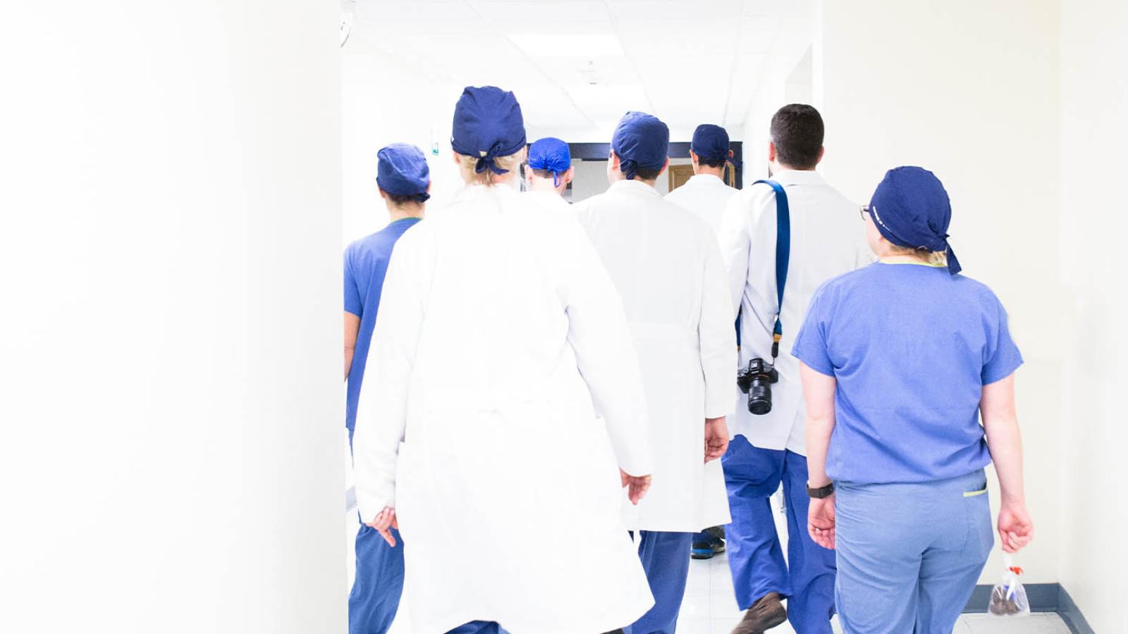 individuals in scrubs walking down a hallway