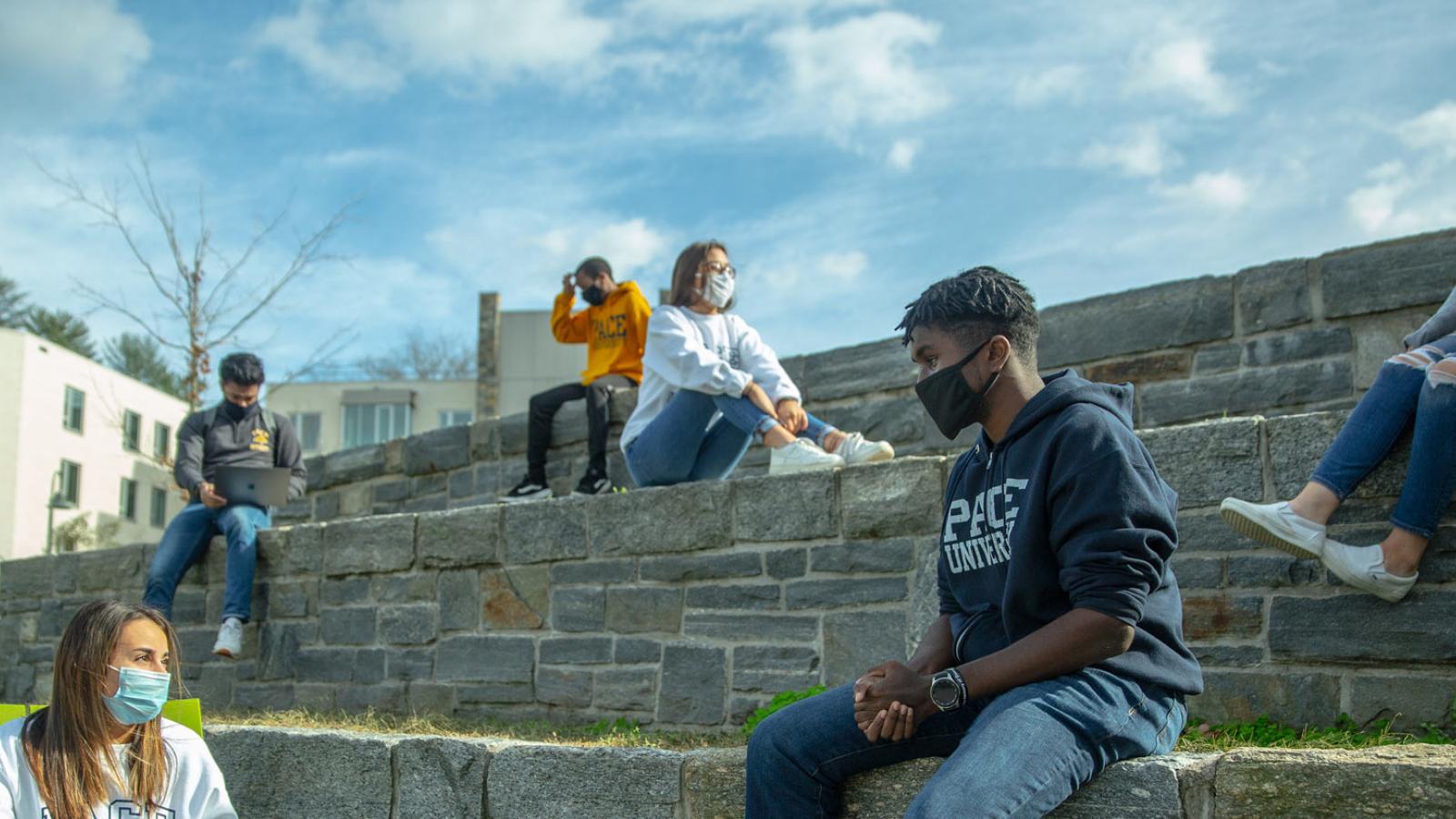 Students talk while sitting outside on the Pleasantville Campus