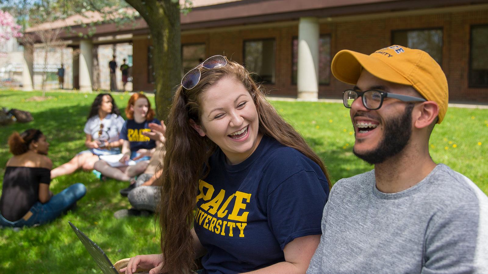 Two students sitting on a bench in front of the library on the NYC campus.