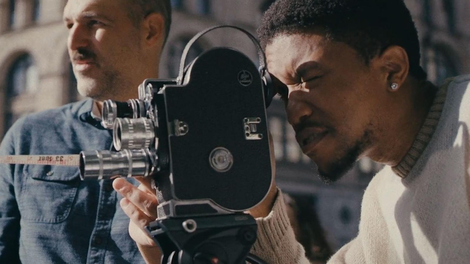 young man looking into a viewfinder of a vintage camera
