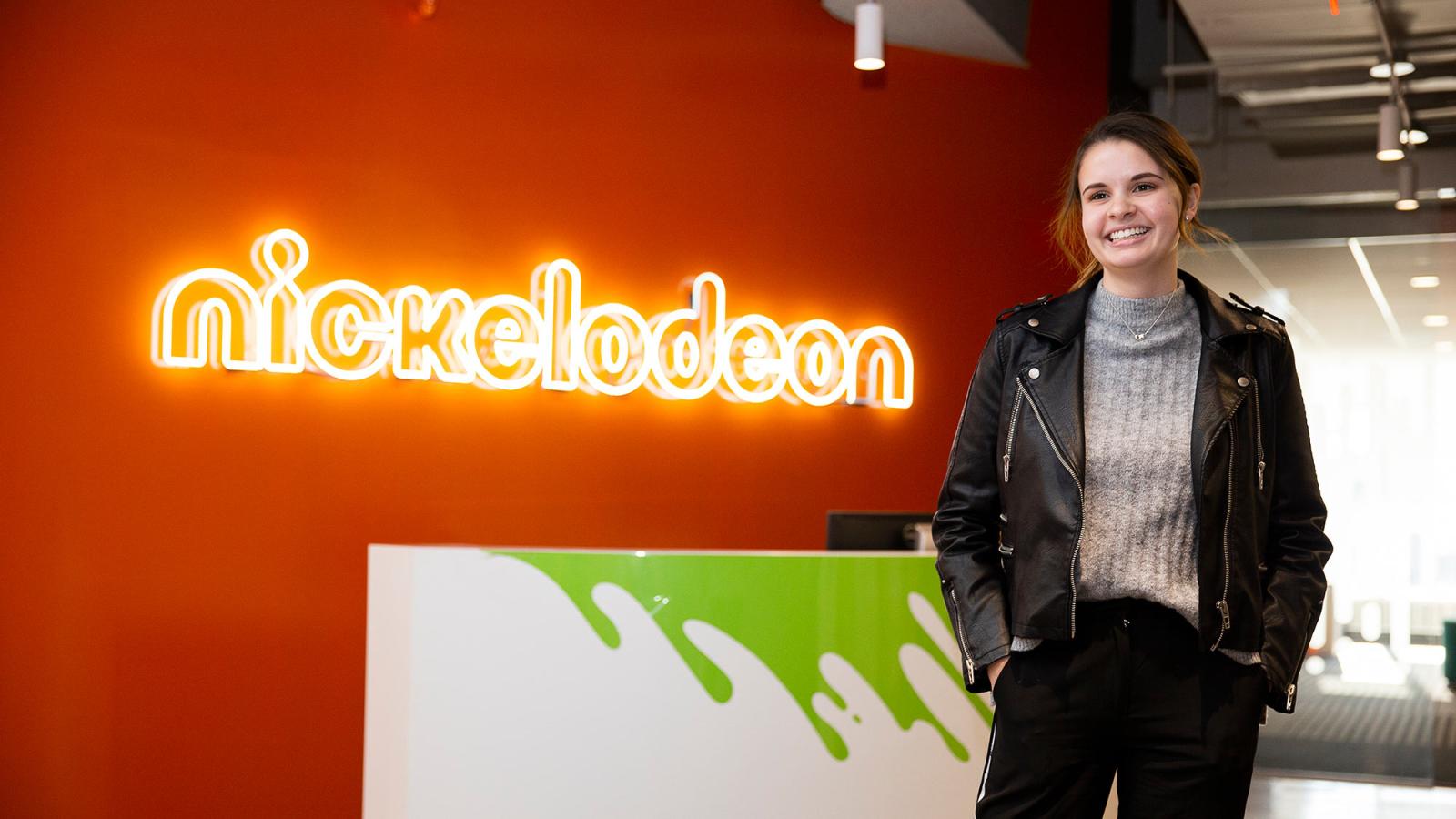 Pace University student intern standing in front of the Nickelodeon sign.