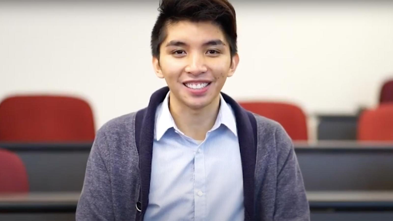 Student sitting at a desk, looking at the camera, talking about his internship.